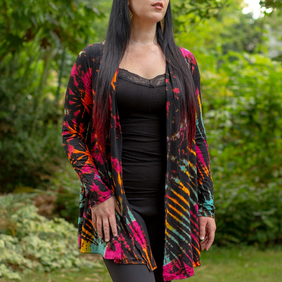 Model wearing Black Rainbow Tie Dye Long Cardigan with stripes and starburst patterns in yellow, gold, orange, turquoise and fuchsia
